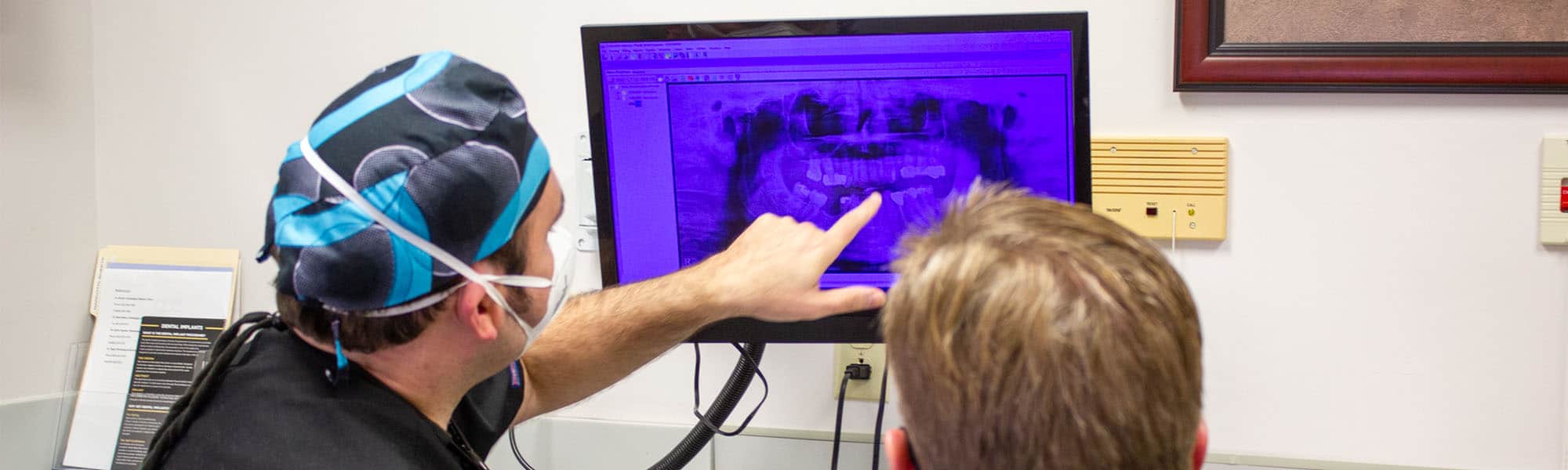 oral surgeon and patient looking at dental implants xray